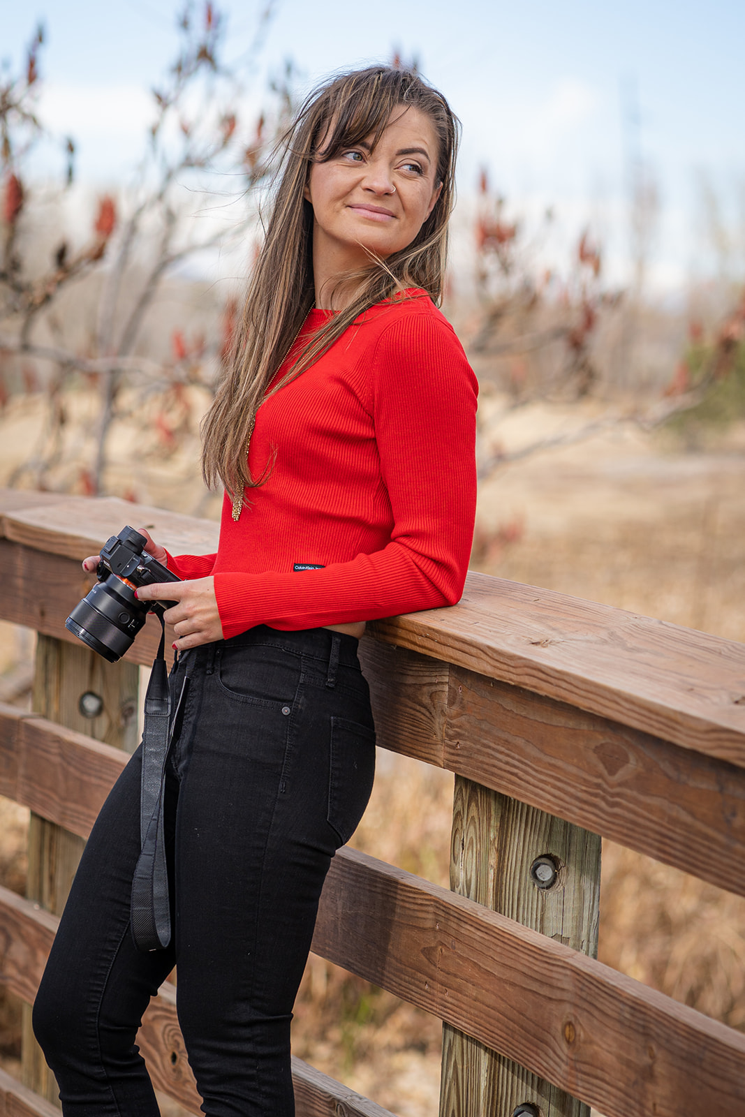 woman leaning on bridge holding a camera