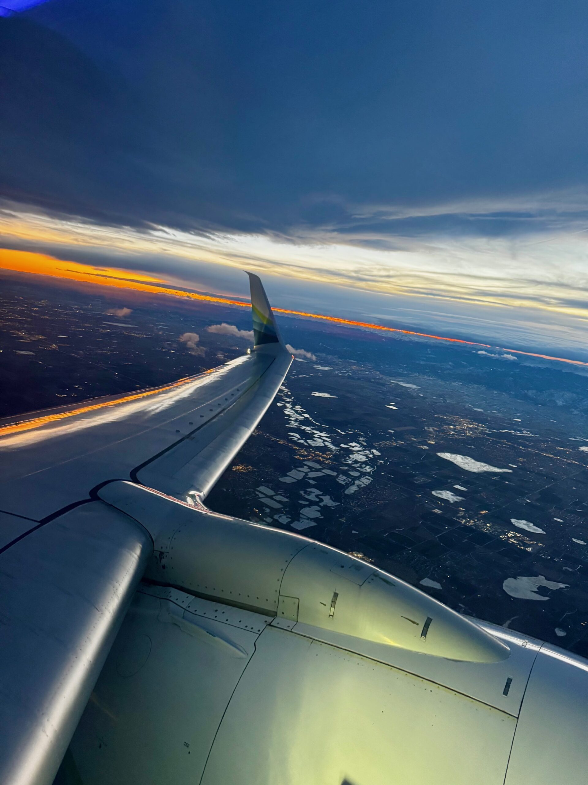 View of clouds and wing from airplane window during sunset