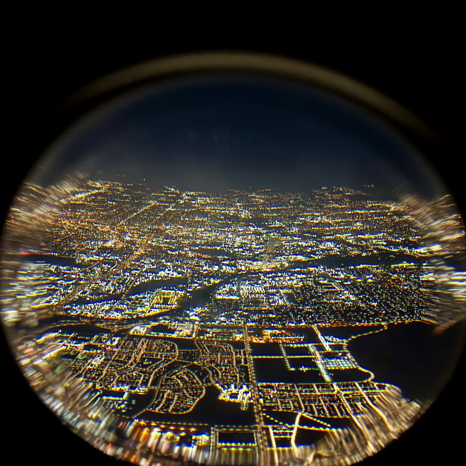 Plane window perspective showing night lights at 35,000 feet

